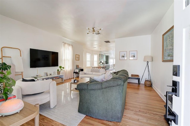 living room featuring light wood-style floors, baseboards, and visible vents