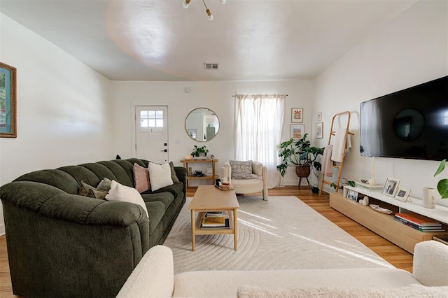 living area featuring baseboards, wood finished floors, visible vents, and a healthy amount of sunlight