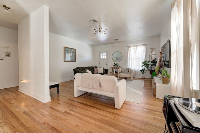 living area featuring light wood finished floors, visible vents, and baseboards