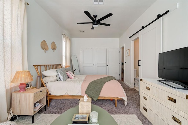 bedroom with a closet, light colored carpet, visible vents, a barn door, and ceiling fan