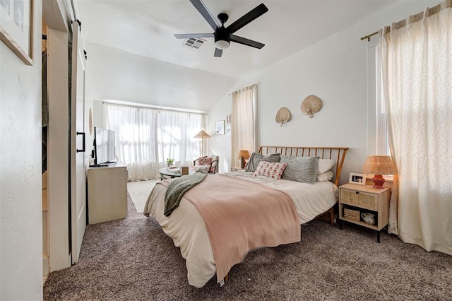 carpeted bedroom with lofted ceiling, visible vents, ceiling fan, and a barn door