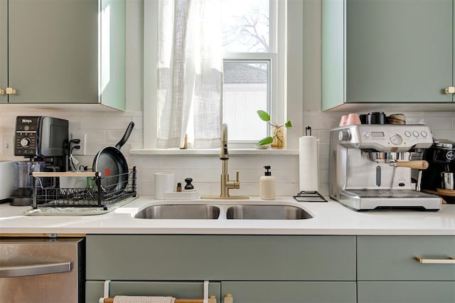 kitchen with green cabinetry, decorative backsplash, light countertops, and a sink