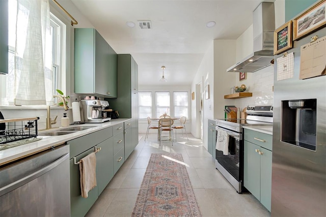 kitchen featuring stainless steel appliances, a sink, visible vents, light countertops, and wall chimney range hood