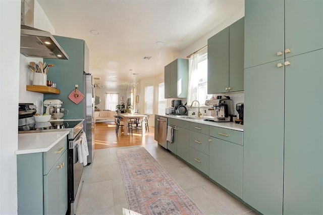 kitchen with appliances with stainless steel finishes, range hood, light countertops, a sink, and light tile patterned flooring