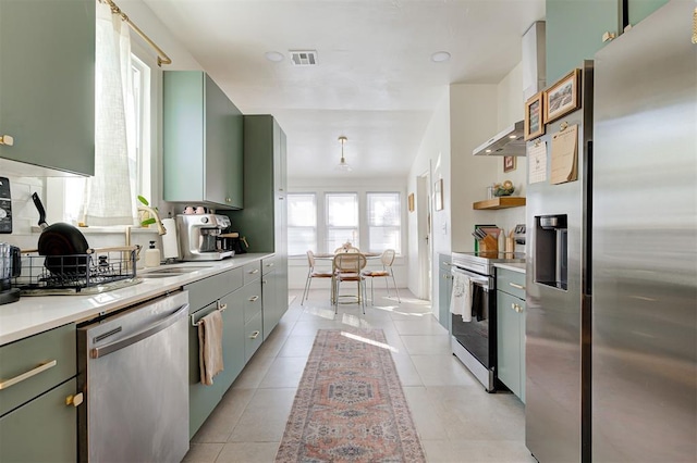 kitchen featuring visible vents, appliances with stainless steel finishes, light countertops, wall chimney range hood, and light tile patterned flooring