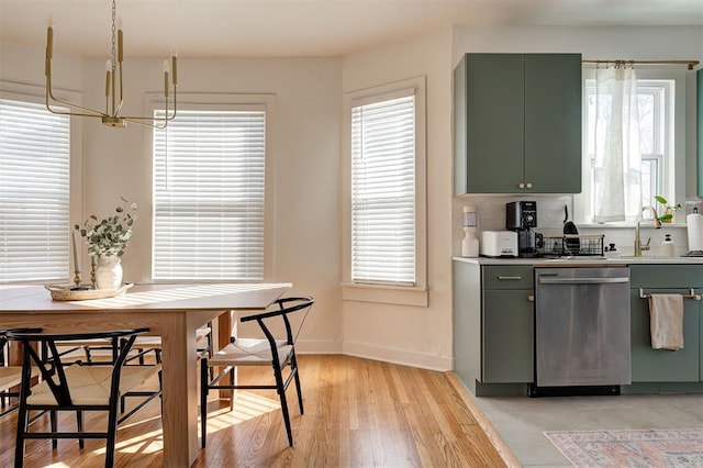 kitchen with a sink, baseboards, green cabinets, light countertops, and dishwasher