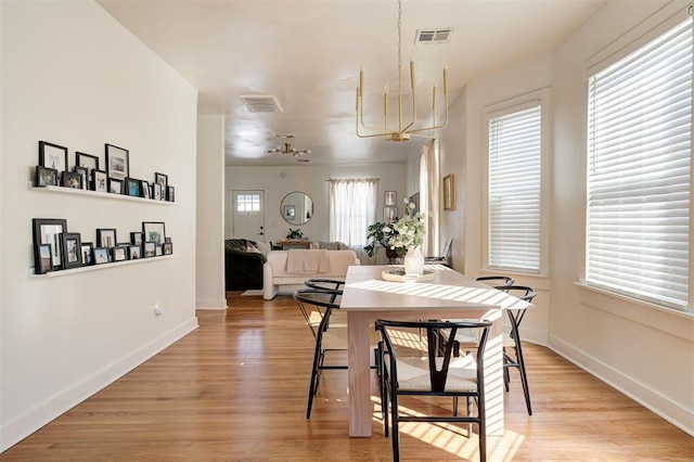 dining area featuring a chandelier, baseboards, visible vents, and light wood finished floors