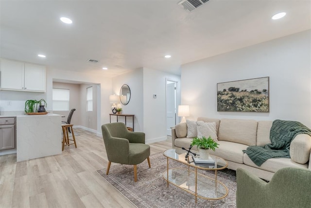 living area with light wood-style flooring, visible vents, baseboards, and recessed lighting