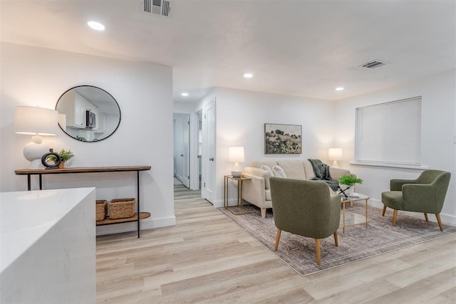 living room featuring baseboards, recessed lighting, visible vents, and light wood-style floors