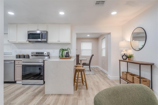 kitchen with stainless steel appliances, light countertops, white cabinets, and a kitchen breakfast bar