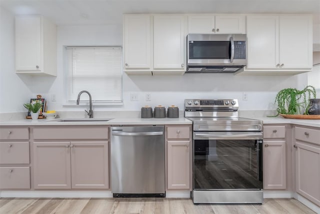 kitchen featuring light countertops, appliances with stainless steel finishes, a sink, and white cabinets