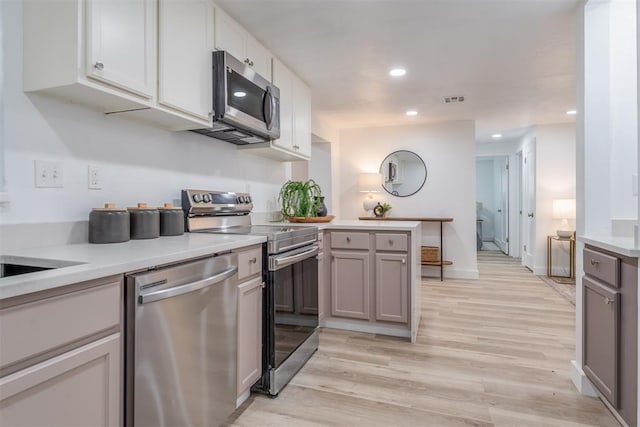 kitchen featuring light countertops, appliances with stainless steel finishes, a peninsula, and gray cabinets