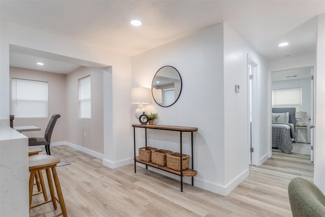 corridor featuring baseboards, recessed lighting, and light wood-style floors