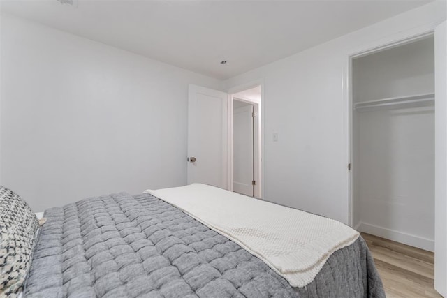 bedroom featuring light wood-type flooring, baseboards, and a closet