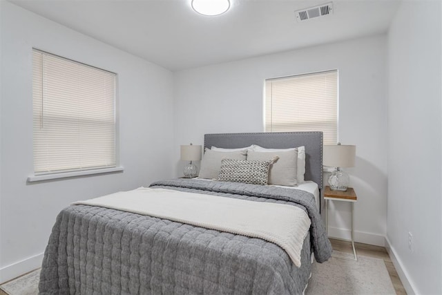 bedroom featuring visible vents, light wood-style flooring, and baseboards