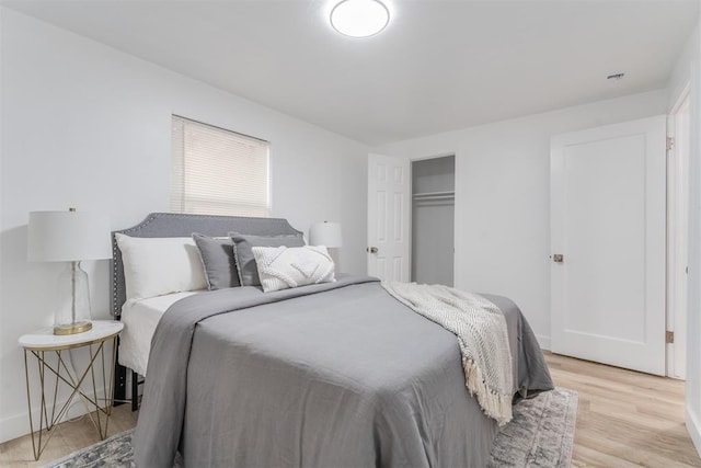 bedroom featuring light wood-style floors, baseboards, and a closet