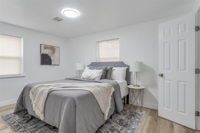 bedroom featuring light wood-type flooring, visible vents, and baseboards