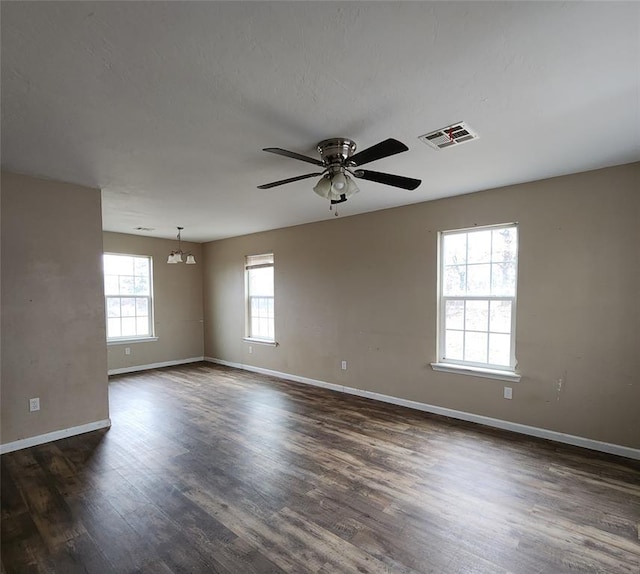 empty room featuring baseboards, visible vents, dark wood finished floors, and a ceiling fan