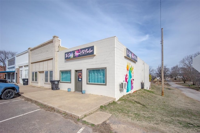 view of property with uncovered parking and a wall mounted AC