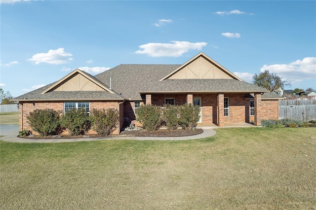 view of front of home with a shingled roof, a front yard, and brick siding