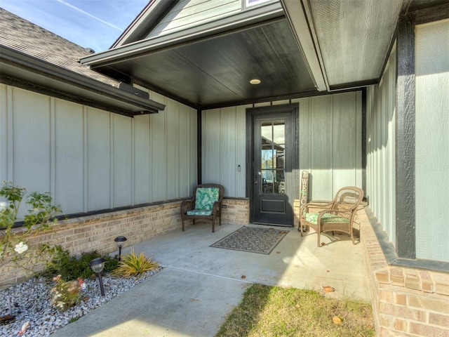 view of exterior entry featuring board and batten siding and brick siding