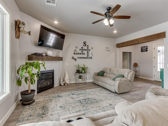 living area with recessed lighting, visible vents, a glass covered fireplace, wood finished floors, and baseboards