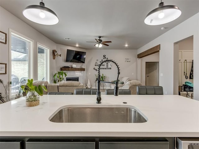 kitchen with a glass covered fireplace, open floor plan, light countertops, and a sink