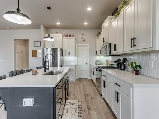 kitchen with decorative light fixtures, stainless steel appliances, tasteful backsplash, light countertops, and a sink