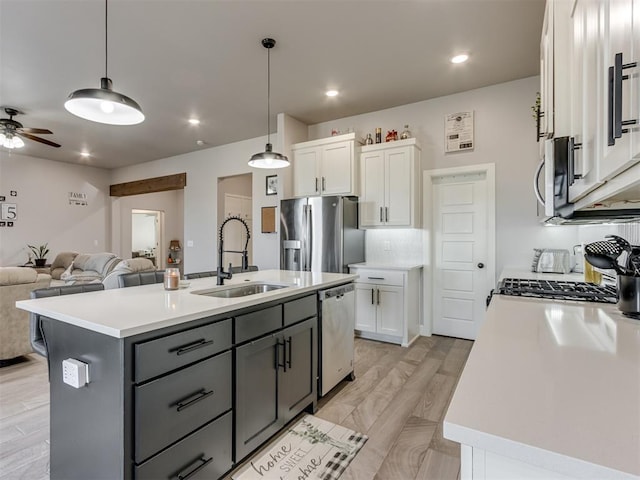 kitchen featuring appliances with stainless steel finishes, white cabinets, a sink, and open floor plan