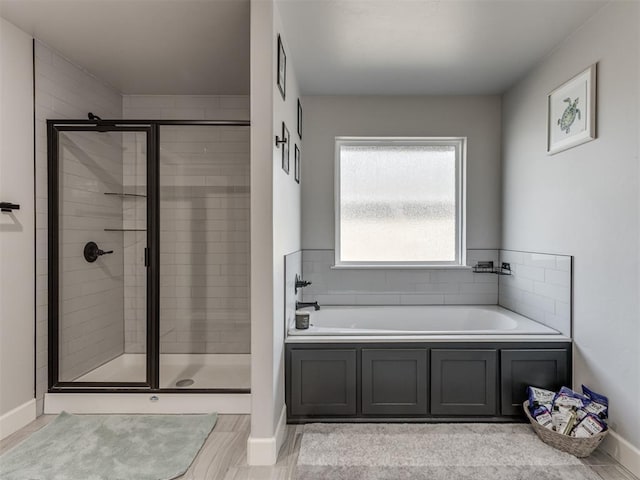 full bath featuring a stall shower, baseboards, and a bath