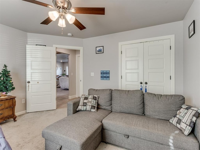 living room with light carpet, ceiling fan, and baseboards