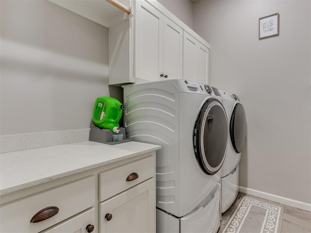 washroom featuring cabinet space, light wood-style flooring, baseboards, and independent washer and dryer