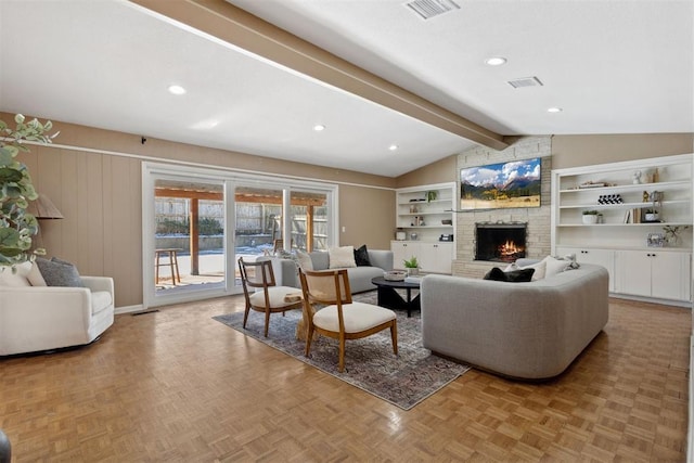 living room with vaulted ceiling with beams, a large fireplace, wood walls, and visible vents