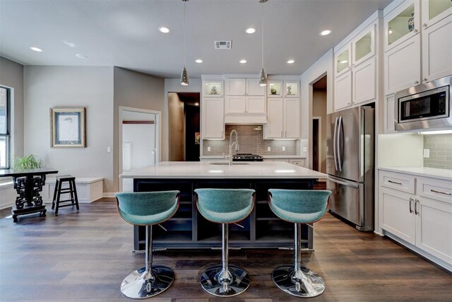 kitchen with glass insert cabinets, visible vents, appliances with stainless steel finishes, and light countertops