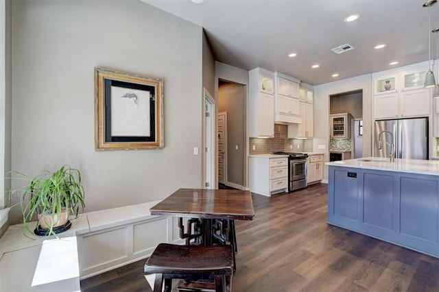 kitchen featuring stainless steel appliances, visible vents, white cabinets, light countertops, and glass insert cabinets