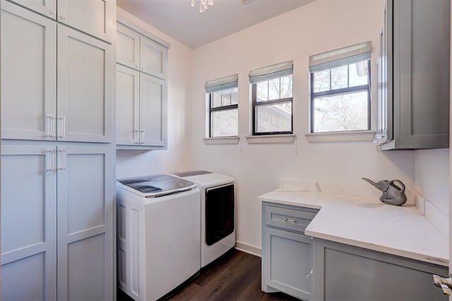 washroom featuring washer and dryer, dark wood-style flooring, cabinet space, and baseboards