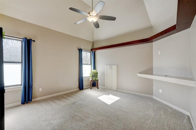 spare room with a ceiling fan, light carpet, vaulted ceiling, and baseboards