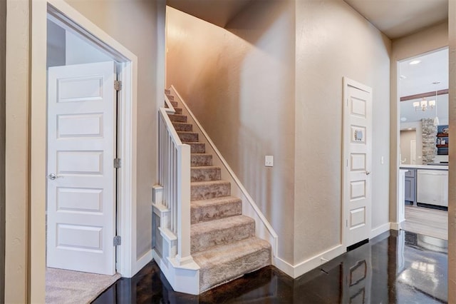 stairs with finished concrete floors, baseboards, and an inviting chandelier