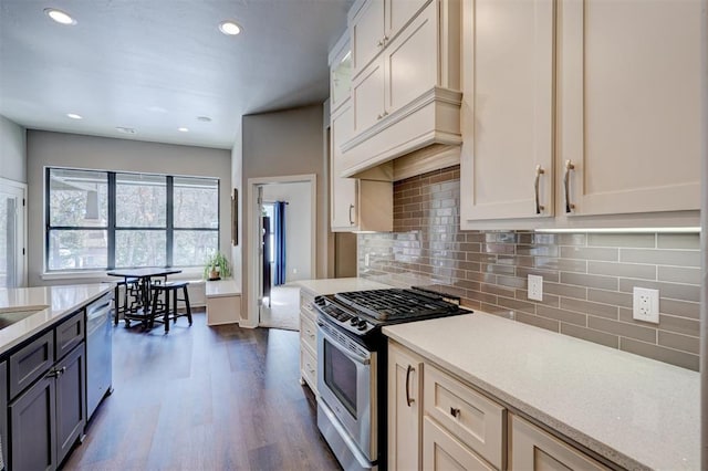 kitchen featuring stainless steel gas range oven, dark wood-style floors, light countertops, decorative backsplash, and dishwasher