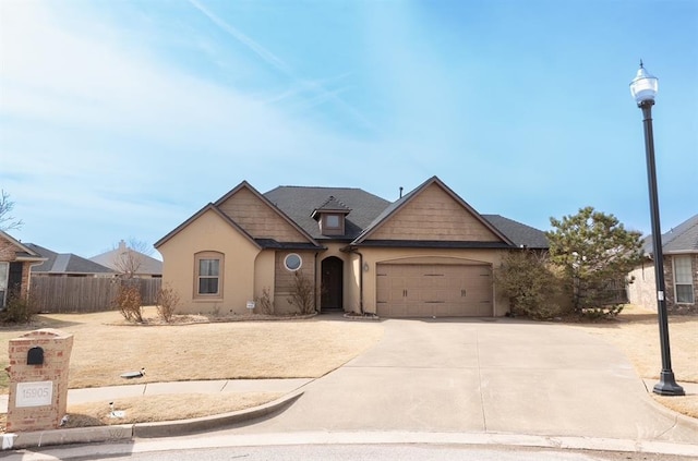 view of front of house with stucco siding, an attached garage, concrete driveway, and fence