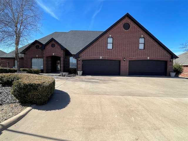 view of front of home featuring driveway, roof with shingles, a garage, and brick siding