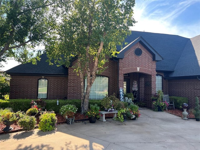 view of front of house featuring a shingled roof and brick siding