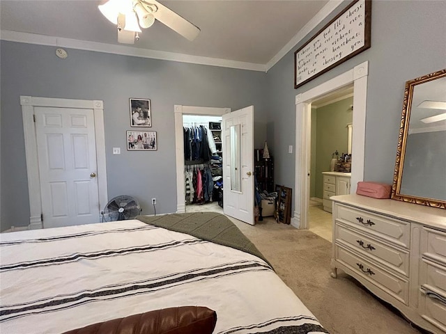 bedroom with a walk in closet, a closet, light colored carpet, ornamental molding, and ensuite bath