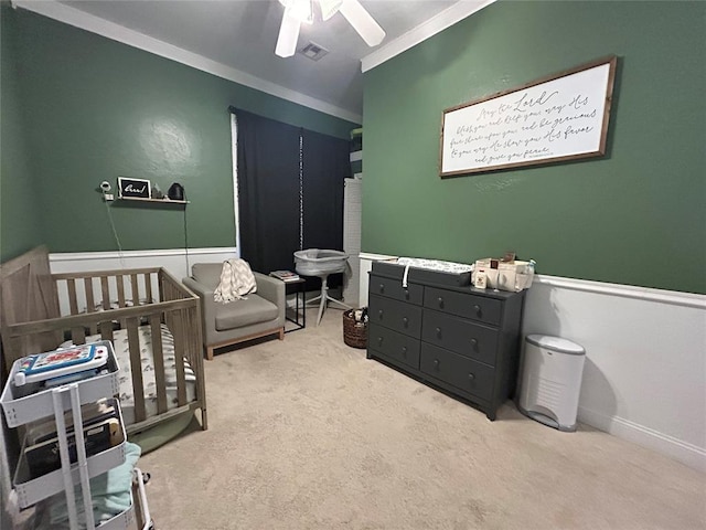 bedroom with a ceiling fan, visible vents, a nursery area, carpet, and crown molding