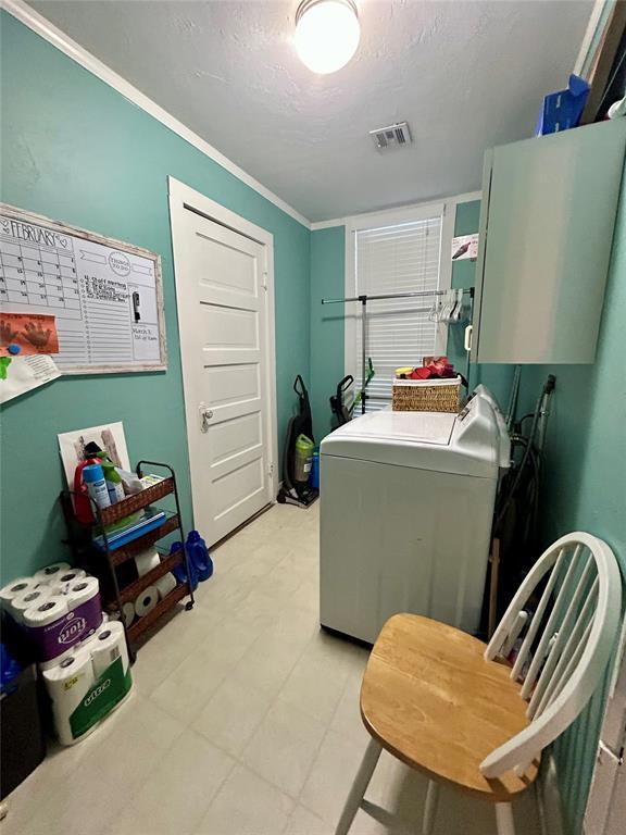 laundry room featuring washing machine and dryer, visible vents, ornamental molding, cabinet space, and light floors