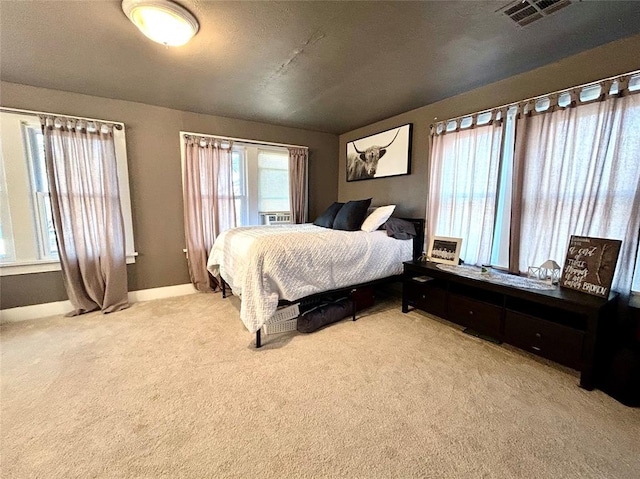 bedroom featuring baseboards, visible vents, and light colored carpet