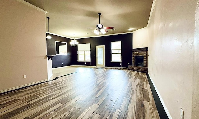 unfurnished living room featuring ornamental molding, a ceiling fan, a fireplace, and wood finished floors