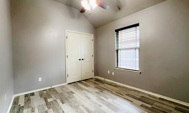 unfurnished bedroom with light wood finished floors, baseboards, a ceiling fan, lofted ceiling, and a closet