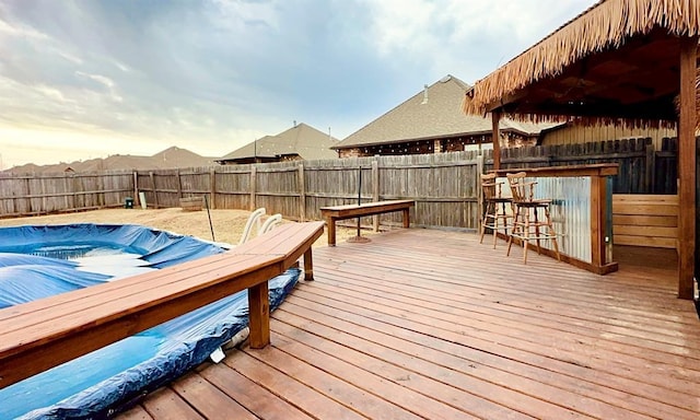 deck featuring an outdoor bar, a fenced backyard, and a fenced in pool