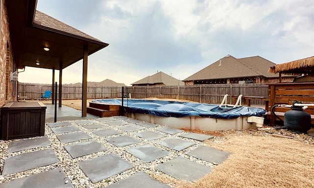 pool at dusk featuring a patio area, a fenced backyard, and a fenced in pool